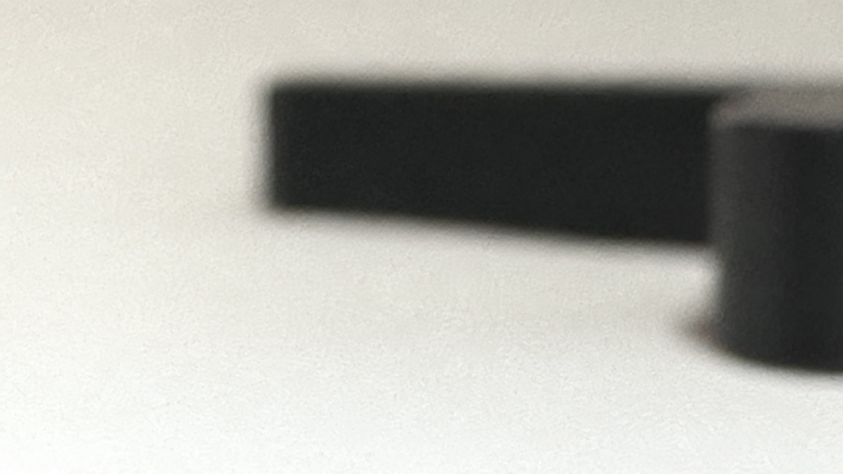 Soft-focus detail of the black Neebee object against a warm off-white surface.